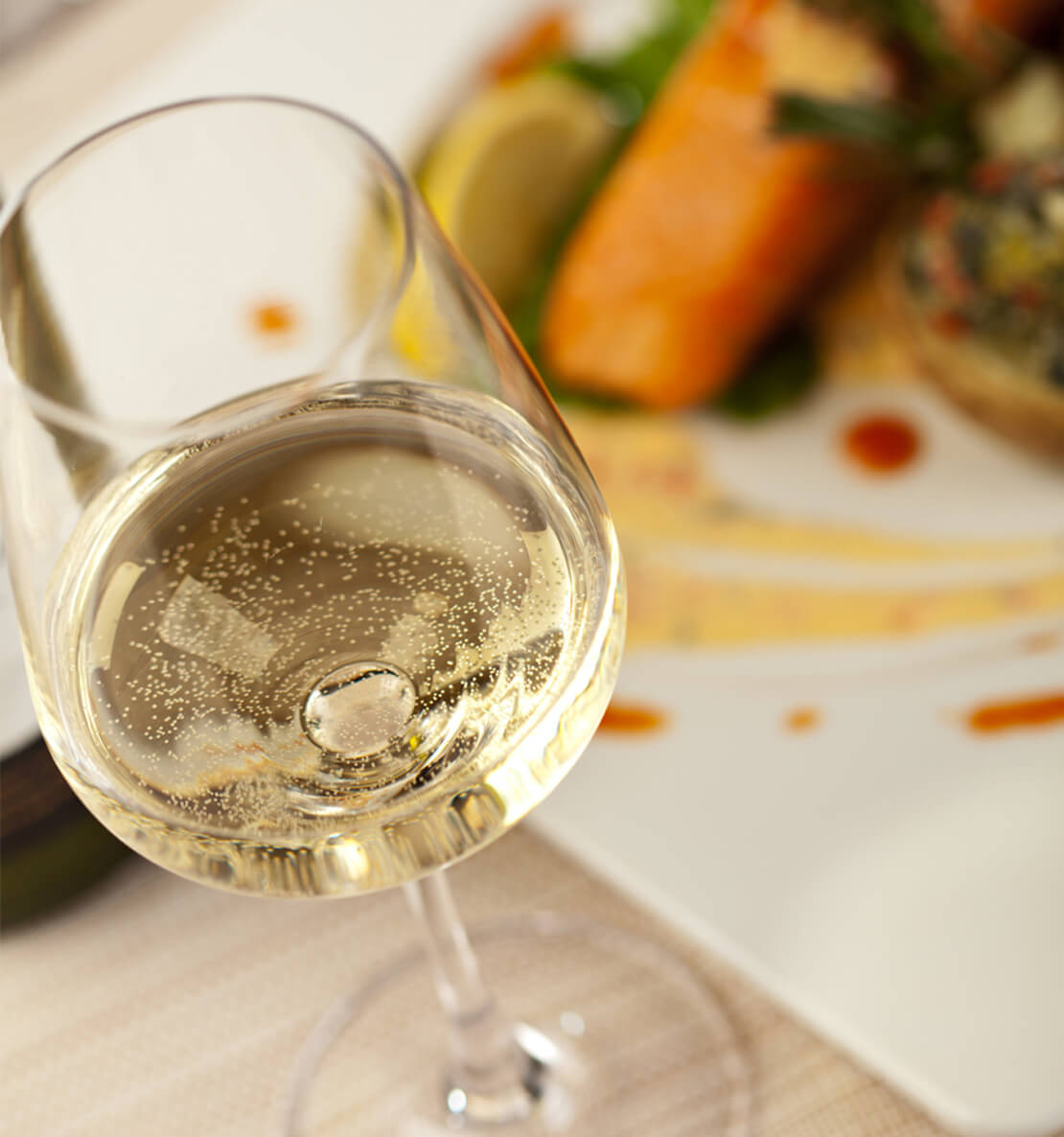 The Lord Lyndoch Barossa Restaurant photo of a glass of white wine with a blurred image of the salmon main course.